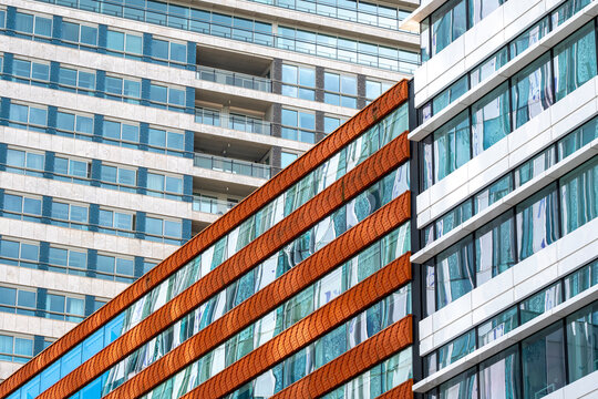 A vibrant modern building showcases an artistic combination of reflective glass panels and horizontal bands, emphasizing contemporary design and architectural innovation.