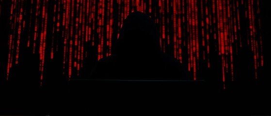 hooded hacker online security concept in darkness with red digits background

