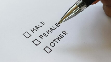 Close up of confused young asian or indian bigender or transgender person hand holding pen for choosing gender identity colum in a page. Concept of identity crisis, confusion or dysphoria.