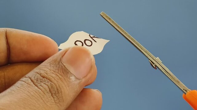 Closeup of hand holding white paper with porn word text written on it cut using scissor. stop porn addiction habit concept.