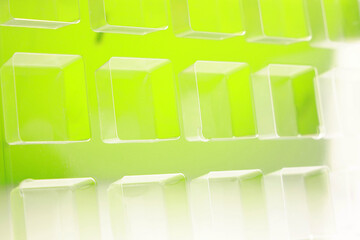 An industrial transparent square thermoforming mold made of plastic as a packaging solution for industrial products. Foil cubes on a green background and shining lights.