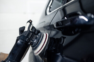 Close up view of brush grinder polishing car paint inside repair shop.