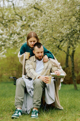 A man and a woman are enjoying a peaceful afternoon in a park. They are seated on a blanket,...