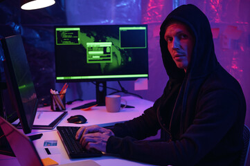 Programmer working with metadata on computers in dark office