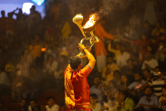 Ganga aarti, Portrait of young priest performing holy river ganges evening aarti at assi ghat in traditional dress with hindu rituals.