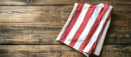 Obraz premium Red and white textile kitchen towel on a brown wooden surface made from old boards top view copy space