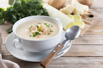 Cauliflower soup in bowl on wooden table