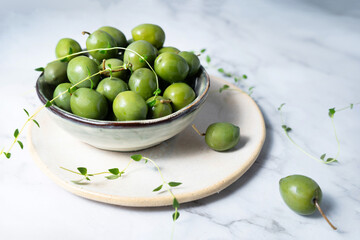 A close-up of marinated green olives in a bowl, fermented foods.
