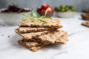 Whole-grain crispbread topped with sesame seeds on a marble background.