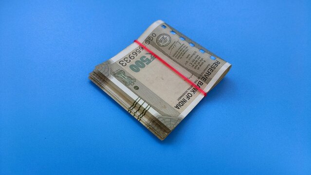 Small bundle of few five hundred rupee indian currency bank note isolated on blue table background with copy space. Closeup top view.