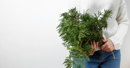 Winter and natural beauty, a woman in a white sweater holding thuja branches