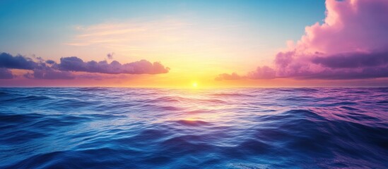 Fototapeta premium Vivid colors of dawn with the sunrise above the ocean The horizon features a sky with clouds and waves A natural background showcasing a gradient of blue and pink Copy space No people present Sunli
