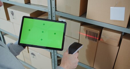 Postal Warehouse Worker Scans Code on Cardboard Box with Barcode Scanner, Checks Package Information, Monitors Parcel Delivery Route. Tablet Computer Display Shows Green Screen Chroma Key. Close Up.