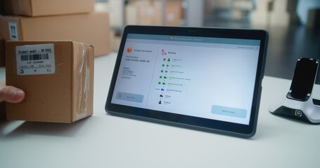 Inventory Manager Scans Code on Cardboard Box with Barcode Scanner, Checks Parcel Information. Tablet Computer Screen Shows Delivery Tracking System for Monitoring Package with Online Orders. Close Up