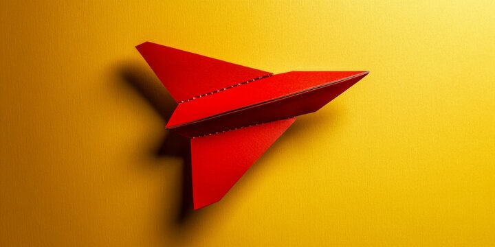 Top view of red paper airplane on yellow background with customizable space for text