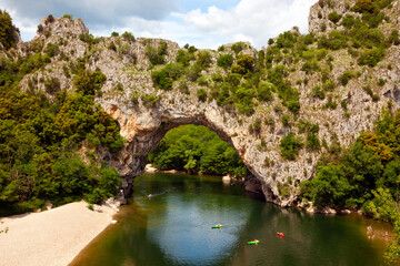 Naklejka premium Canoes below the natural stone arch Pont d'arc across the Ardèche river