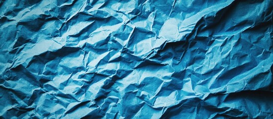 Fototapeta premium Close up of a blue crumpled piece of construction paper used as a background with blank space for design Blue creased crumpled paper backdrop. with copy space image. Place for adding text or design