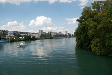 Obraz premium Serene river with a boat and modern buildings