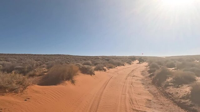 Off road desert sandy trail 4x4 Utah into sun POV. Off road trail riding in 4x4 all terrain vehicle for sport and recreation. Desert landscape, dusty trails and recreation areas. Southwest Utah