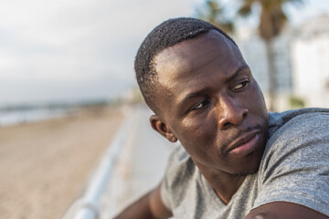 Portrait of young black man with sunset sky and palm trees on the promenade in the background