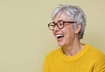 Portrait of happy gray-haired old woman in yellow sweater laughing