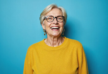 Portrait of a gray-haired mature woman in a yellow sweater on a blue background