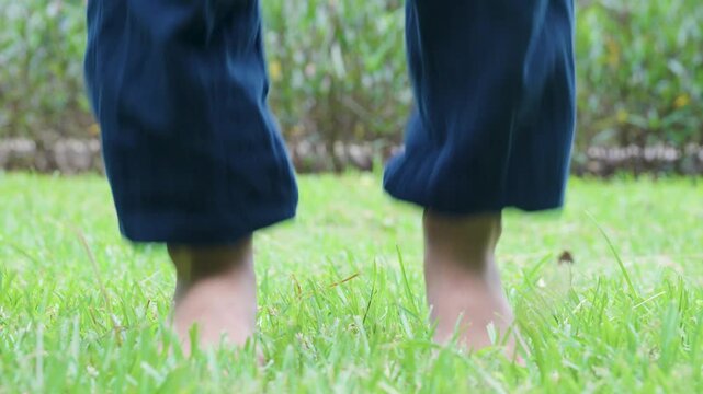 A little child is exercising in the park barefoot, jumping and stomping their feet