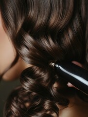 Fototapeta premium Professional hairstylist creating elegant glossy curls with a curling iron, soft brown hair texture, warm lighting, close-up shot with ample copyspace.