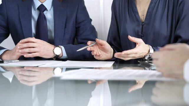 Business partners or lawyers are discussing contract papers during a meeting, negotiating and making decisions together. Business people concept, close up