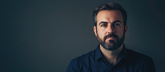 Handsome construction engineer portrait on dark gray background showcasing strong facial features and ample copyspace for text with soft lighting.