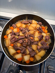 Beef and potato stew cooking in the pan.