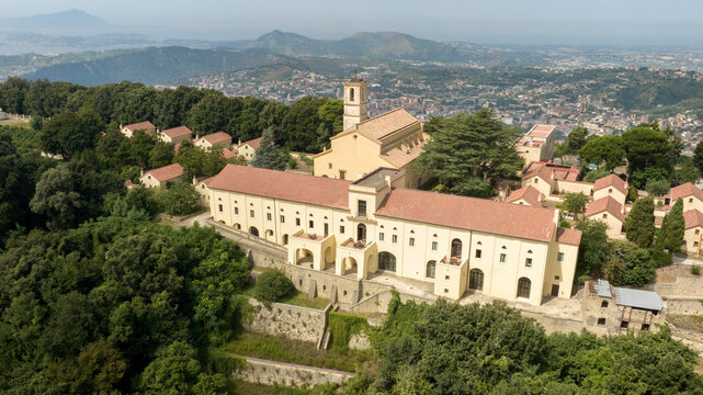 Aerial view of the Eremo dei Camaldoli in Naples, Italy. It's a ancient religious complex with a Catholic church and is located on top of a mountain. The hermitage overlooks the city in the background