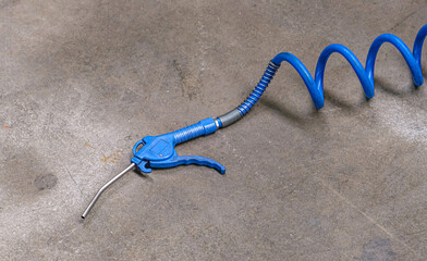 Industrial Air compressor gun with coiled hose on concrete floor. Pneumatic air hammer chisel, regulates the airflow of the compressor.