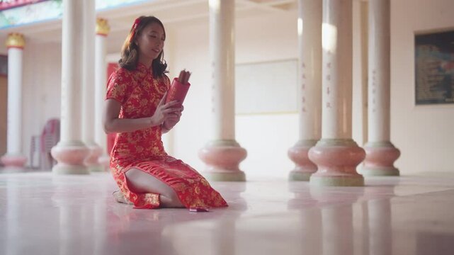 A woman in a red dress is kneeling on the floor and reading a book. Concept of calm and focus as the woman is fully engaged in her reading. The red dress adds a touch of elegance