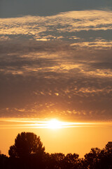 Breathtaking sunset over a tranquil landscape with silhouetted trees and a colorful sky