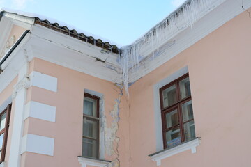 A Damaged Corner of a Building Showcasing Icicles and Cracks Indicating Structural Weakness