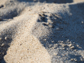 Close-up of fine sand texture with shadows and sunlight creating a natural pattern