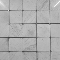 evocative black and white image texture of vertical surface of square marble tiles