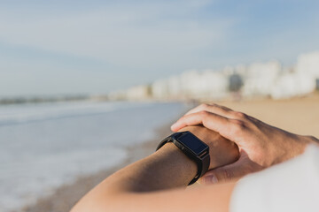 Caucasian man checking smartwatch while exercising on the beach
