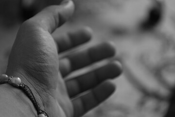 Outstretched Hand in Black and White
A monochrome image of a hand reaching out with a bracelet, set against a blurred background. It conveys simplicity, connection, and offering.