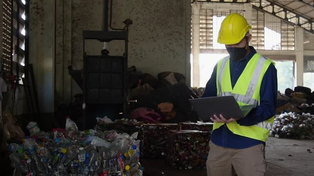 Asian quality inspector using laptop to check quality of waste compaction or plastic compaction in waste industry at waste sorting plant.