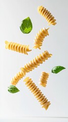 Naklejka premium Several pieces of fusilli pasta and basil leaves are levitating against a minimalist white background. Creating a visually appealing composition that emphasizes the raw ingredients of italian cuisine