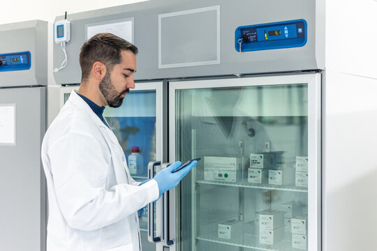 Scientist using tablet checking refrigerated drugs in pharmaceutical laboratory refrigerator