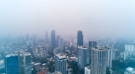 A hazy cityscape featuring tall buildings shrouded in fog, creating a mysterious and subdued urban atmosphere.