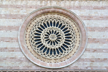 Rose window on the facade of the Basilica of Santa Chiara in the famous medieval town of Assisi, Umbria, Italy