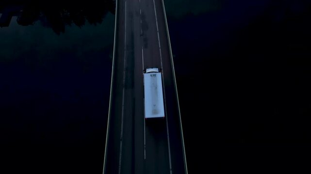 White truck driving on bridge at night with red car overtaking