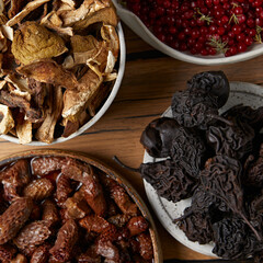 Dried mushrooms and dried fruits in different plates on the table