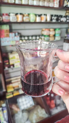 Woman holding a glass of Hibiscus tea in marsa alam herbal shop, egypt