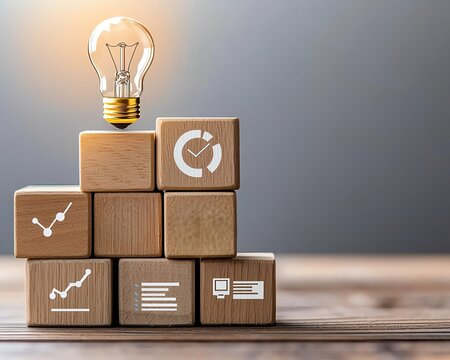 Business growth process featuring a set of wooden blocks with a light bulb, graph, and target icons stacked to illustrate business innovation