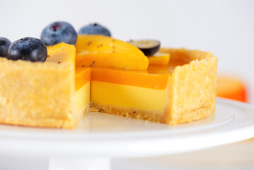 Sliced mango tart with fresh blueberry on a stand. Sugar, sugar substitutes, lactose and gluten free. Vegan dessert.